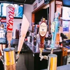 Beer tap handles: Coors Light, Glenshaw Lager, at a dim bar.
