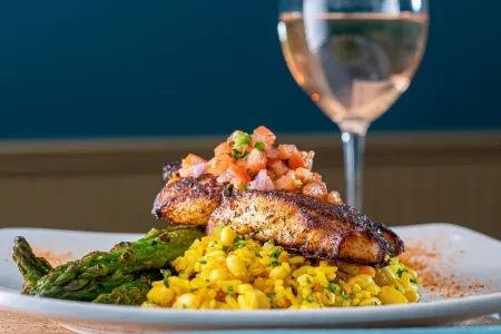 Grilled fish with salsa on yellow rice, asparagus, and rosé wine.