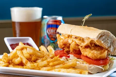 Close-up of a fried seafood sandwich, fries, and ketchup.