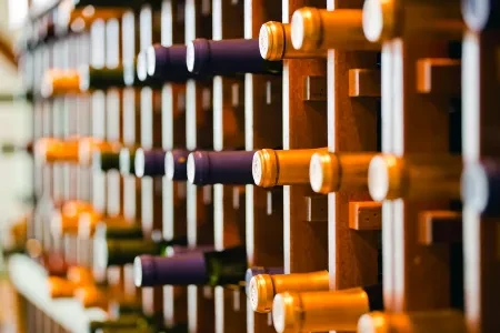 Wine bottles in a wooden rack with gold and purple foil.