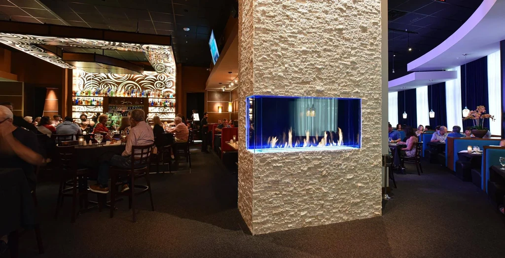Modern restaurant interior: bar, blue fireplace, and blue dining booths.