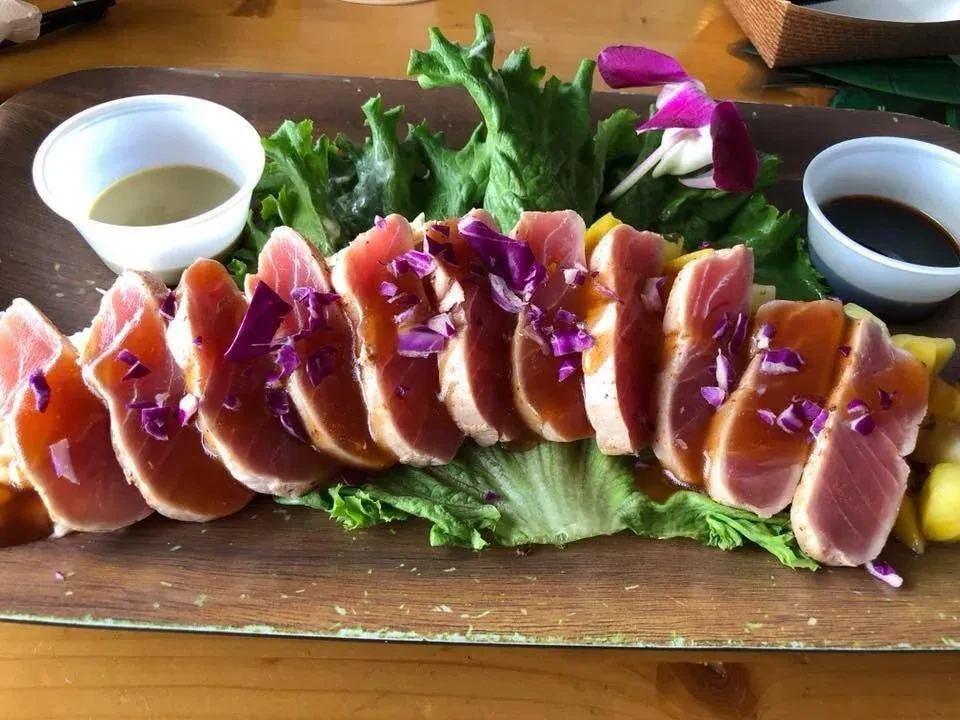 Seared rare tuna slices, lettuce, two dipping sauces, orchid garnish.