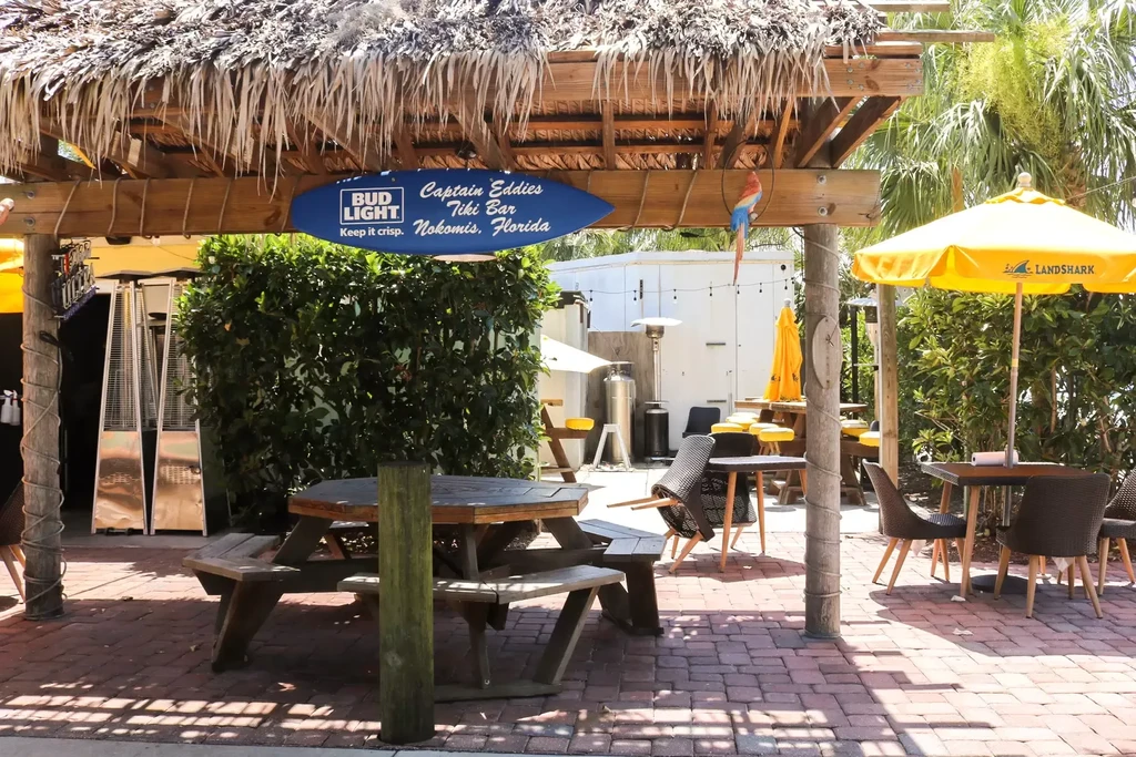 Outdoor Captain Eddies Tiki Bar with thatched roof and picnic table.