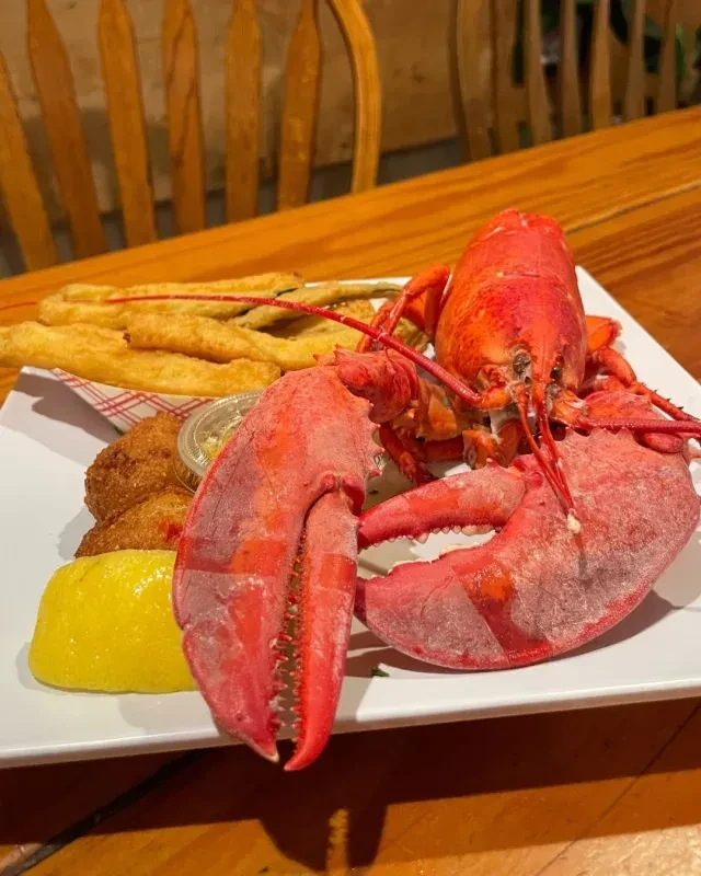 Bright red cooked lobster meal with french fries, sauce, and lemon.