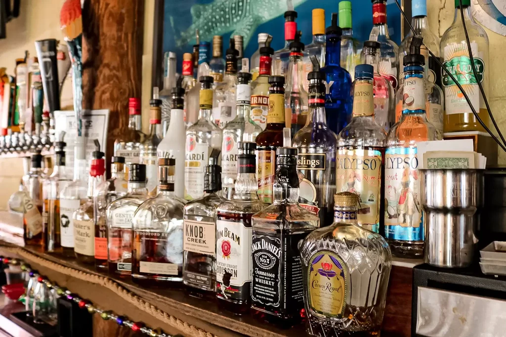 Rows of diverse liquor bottles and beer taps behind a bar.