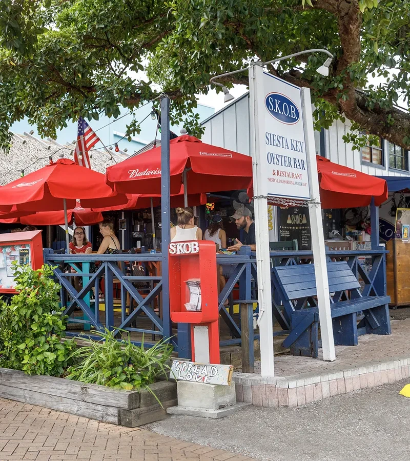 S.K.O.B. patio with red umbrellas, diners, and a "SPREAD LOVE" block.