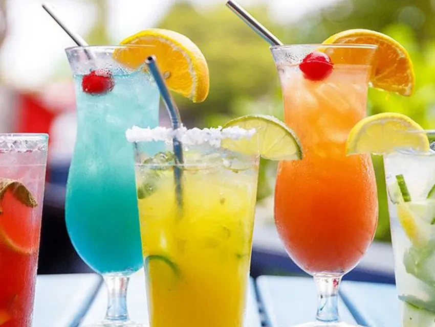 Close-up of five colorful, garnished mixed drinks in a row.