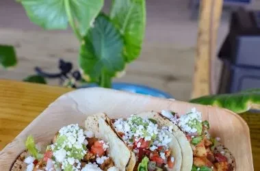 Three soft tacos with seasoned meat, lettuce, salsa, and cheese.