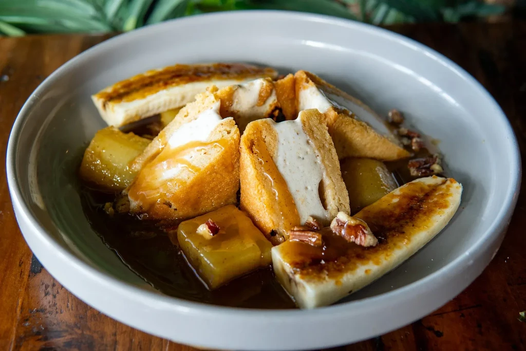 Creamy-filled fried toast with caramelized banana, fruit, nuts, and caramel sauce.
