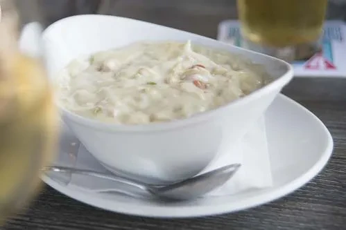 Creamy dish in a white bowl with spoon on a dark wooden table.