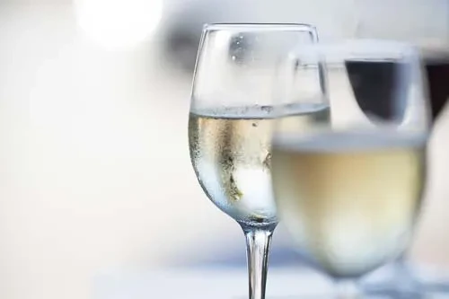 Chilled wine glass with condensation in focus, blurred glasses behind.