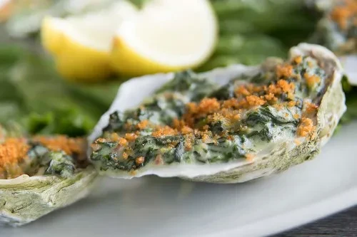Baked oysters in half-shells with creamy green filling and breadcrumbs.