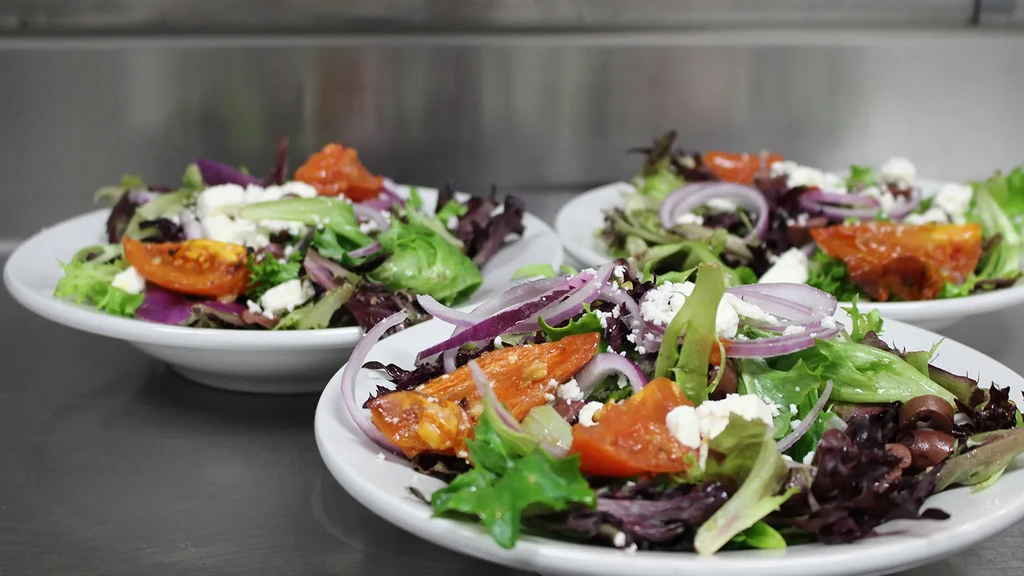 Three plates of fresh colorful salad on a stainless steel surface.