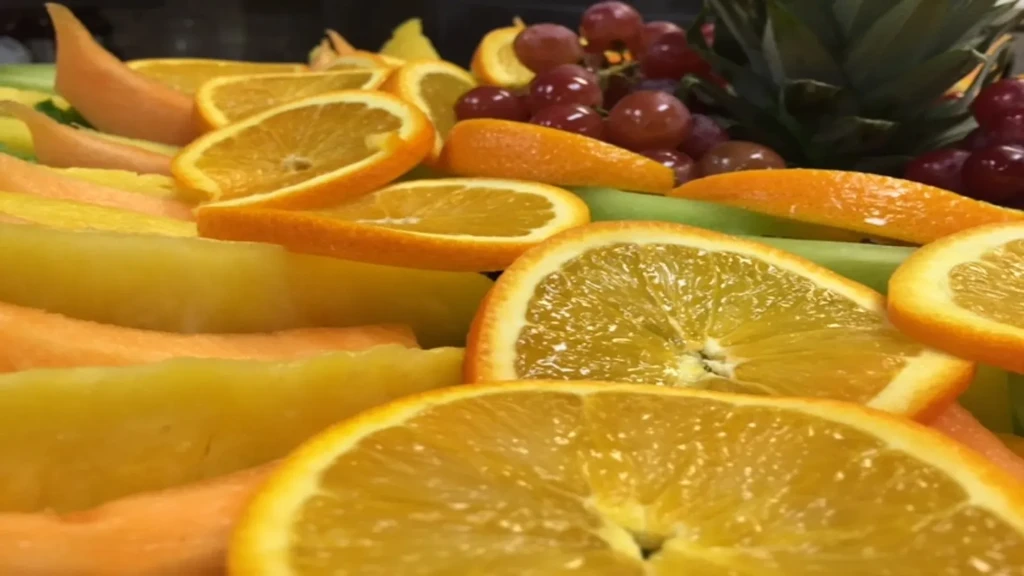 Colorful fruit platter with orange slices, melon, grapes, and pineapple.