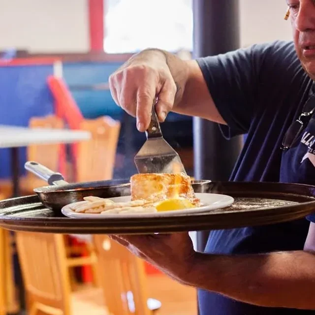 Chef plating golden-brown food with a spatula and lemon.