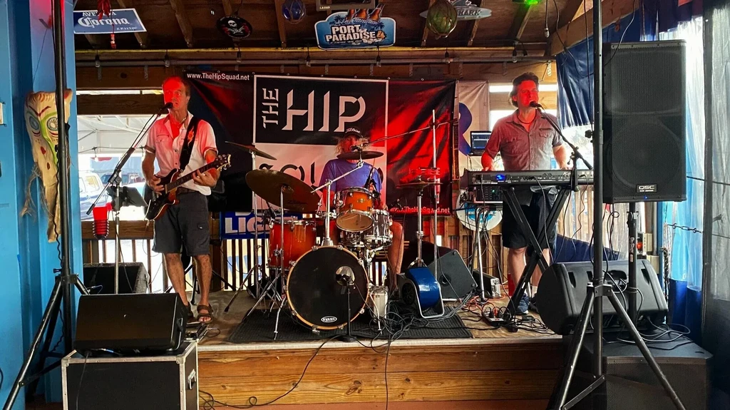 The Hip Squad, a three-piece band, plays live in a casual bar.