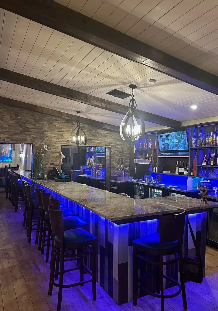Modern bar interior with blue-lit granite counter and stocked liquor shelves.