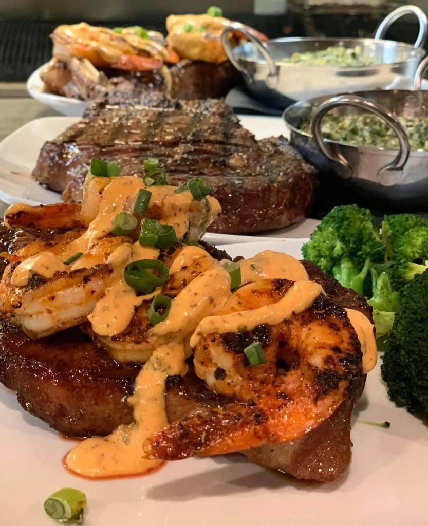 Grilled surf-and-turf with creamy sauce, green onions, and broccoli.