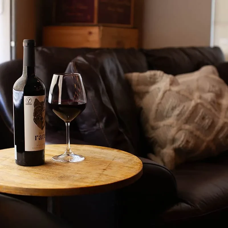 Vegan red wine bottle, glass on table, rustic crates background.