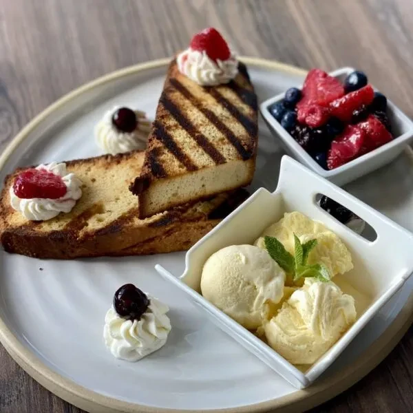 Artistically plated grilled pound cake dessert with ice cream and berries.