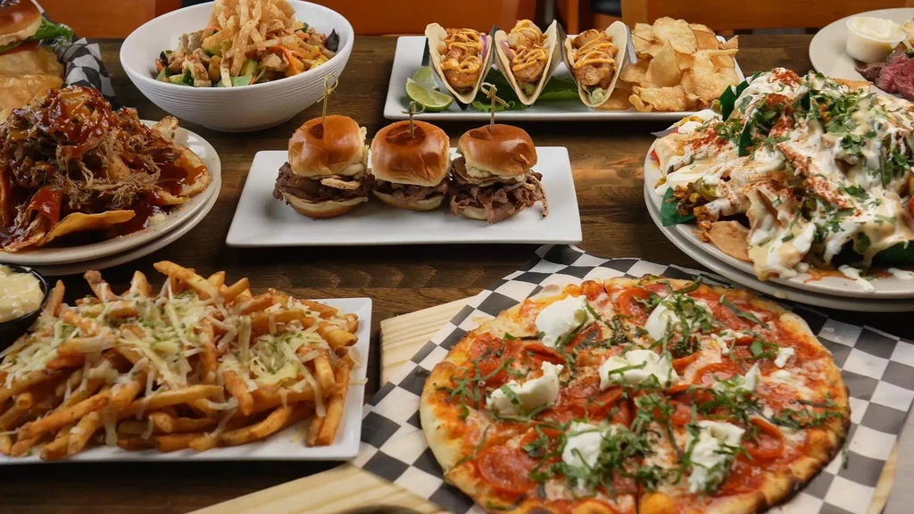 Overhead shot: wooden table laden with a variety of restaurant food.