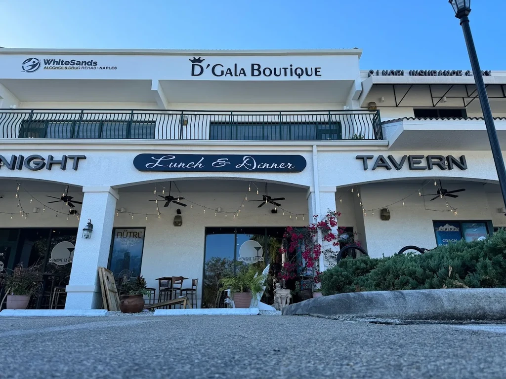 White stucco strip mall with arched alcoves housing various businesses.