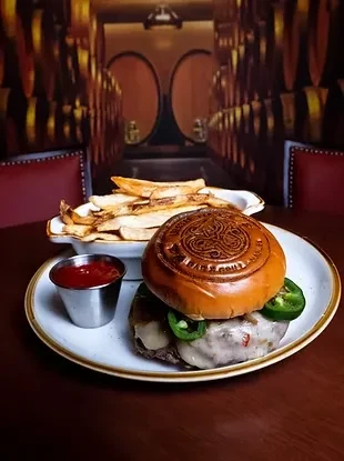 Embossed bun burger, fries, and ketchup in a barrel-lined restaurant.