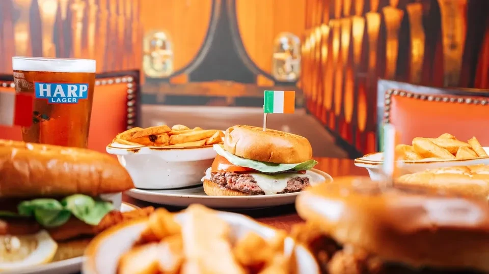 Burgers, fries, and Harp Lager on a table in an Irish pub.