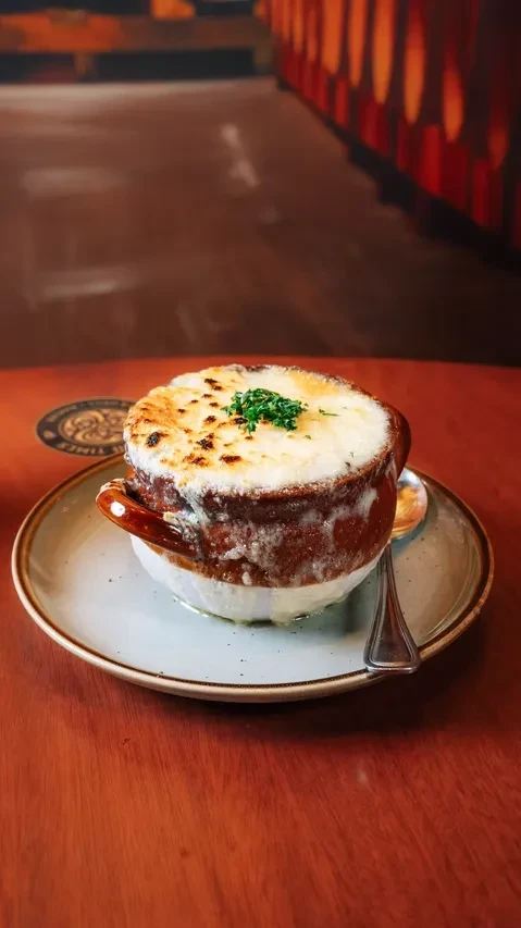 Steaming French onion soup in a crock with melted golden cheese and herbs.