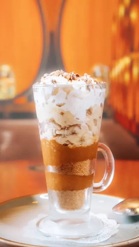 Dessert in glass mug: crumbled base, caramel, fruit, whipped cream.