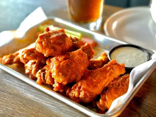 Crispy orange buffalo wings, dipping sauce, and celery sticks.