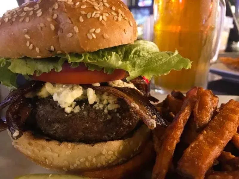 Close-up of a gourmet burger and sweet potato fries with beer.