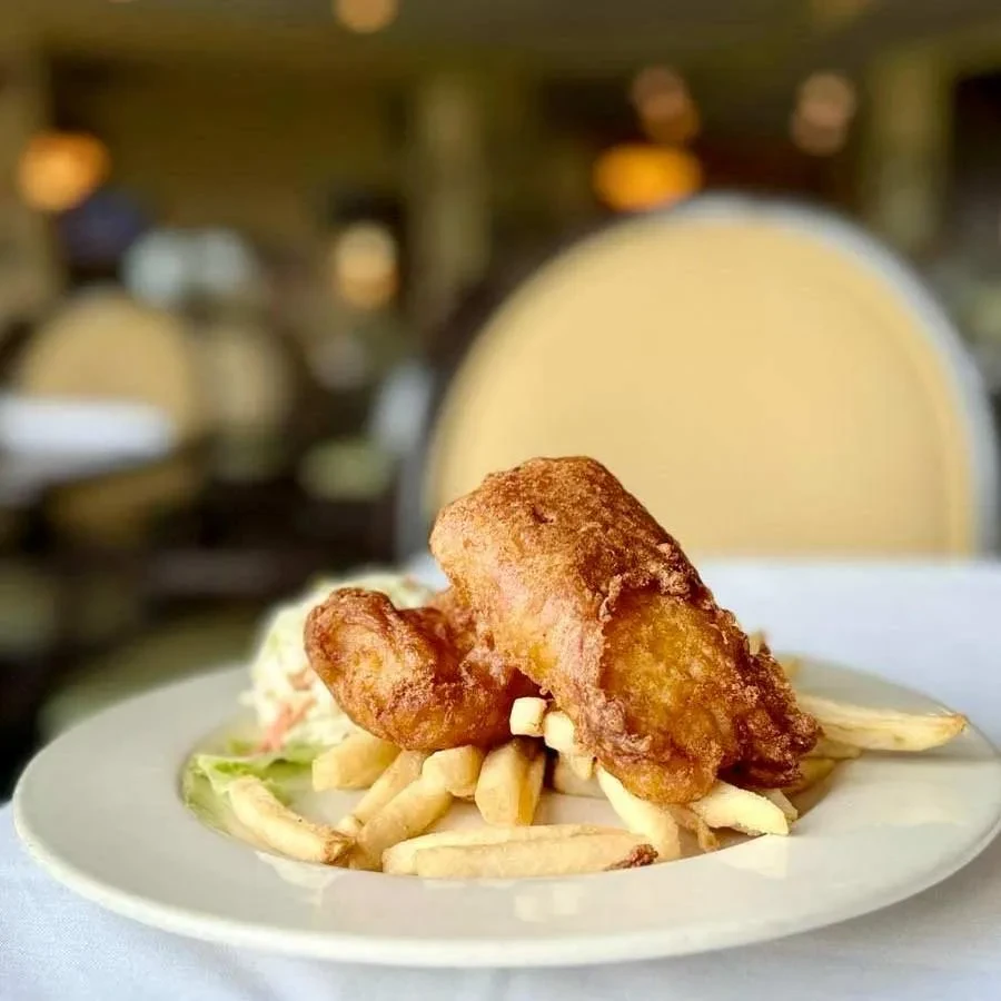 Plate of crispy fried fish, golden fries, and a small green salad.
