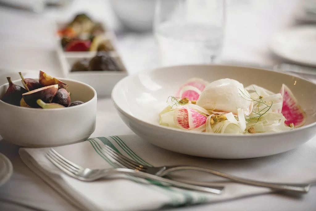 Burrata and fig salad with radishes on a restaurant table.