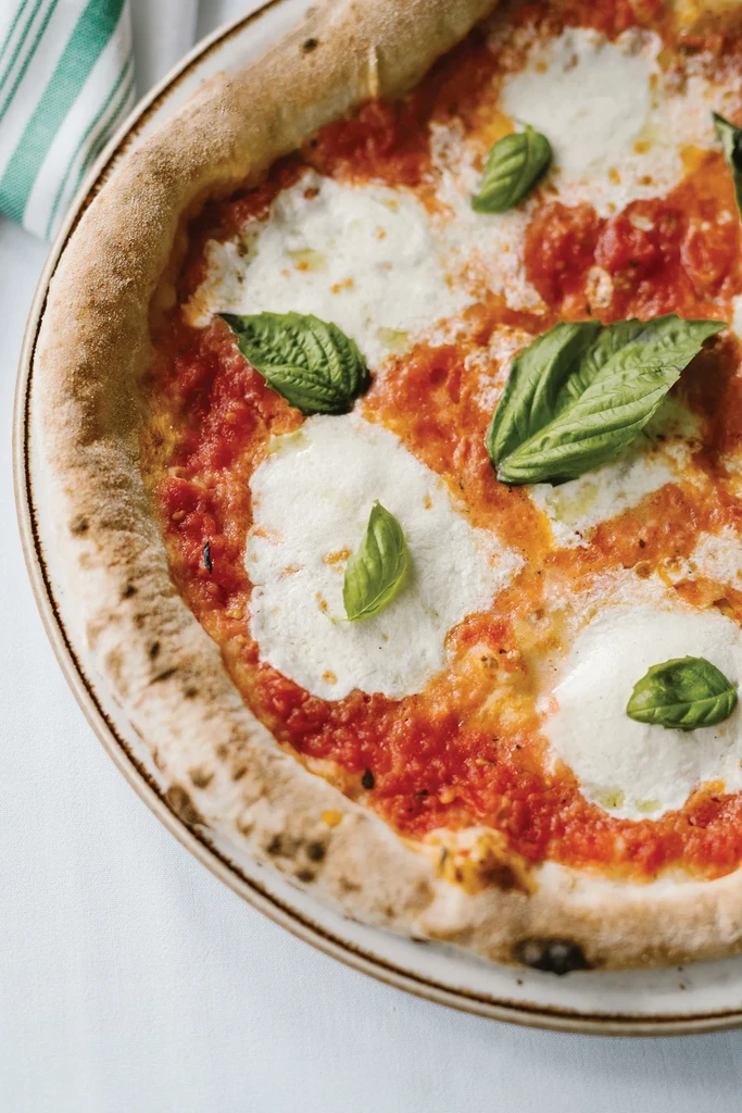 Freshly baked Margherita pizza with charred crust, mozzarella, and basil.