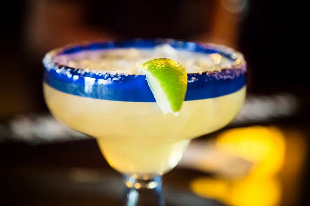 Margarita in a blue-rimmed glass, with salted rim and lime.