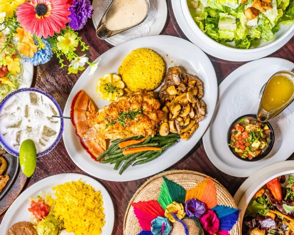 Overhead: Table with grilled lobster, steak, rice, vegetables, salad, margarita.