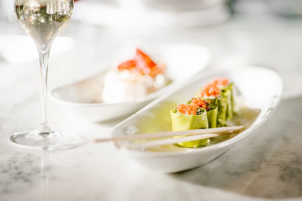 Appetizers: green rolls with roe, chopsticks, and a champagne flute.