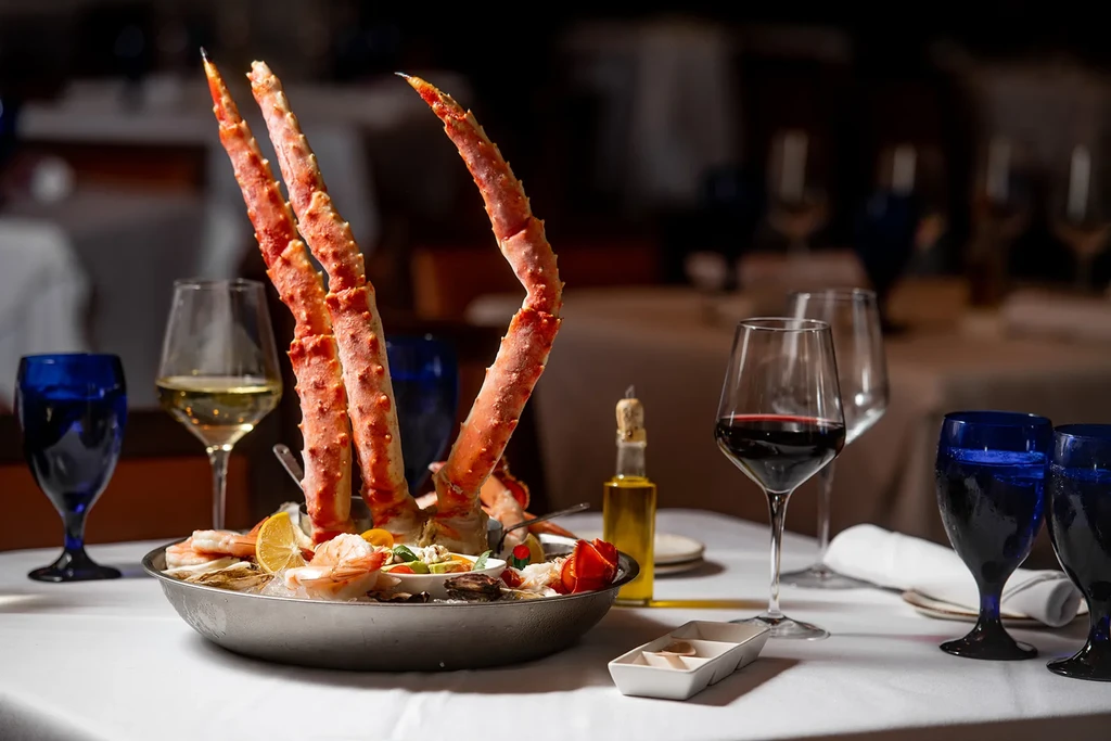 Elegant platter with King Crab legs, shrimp, oysters, lemon, and wine.
