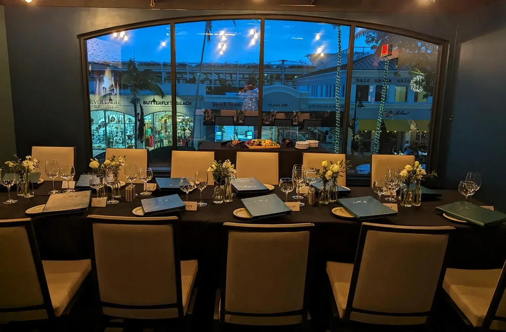Elegant restaurant table set for dinner, overlooking a lively evening street.