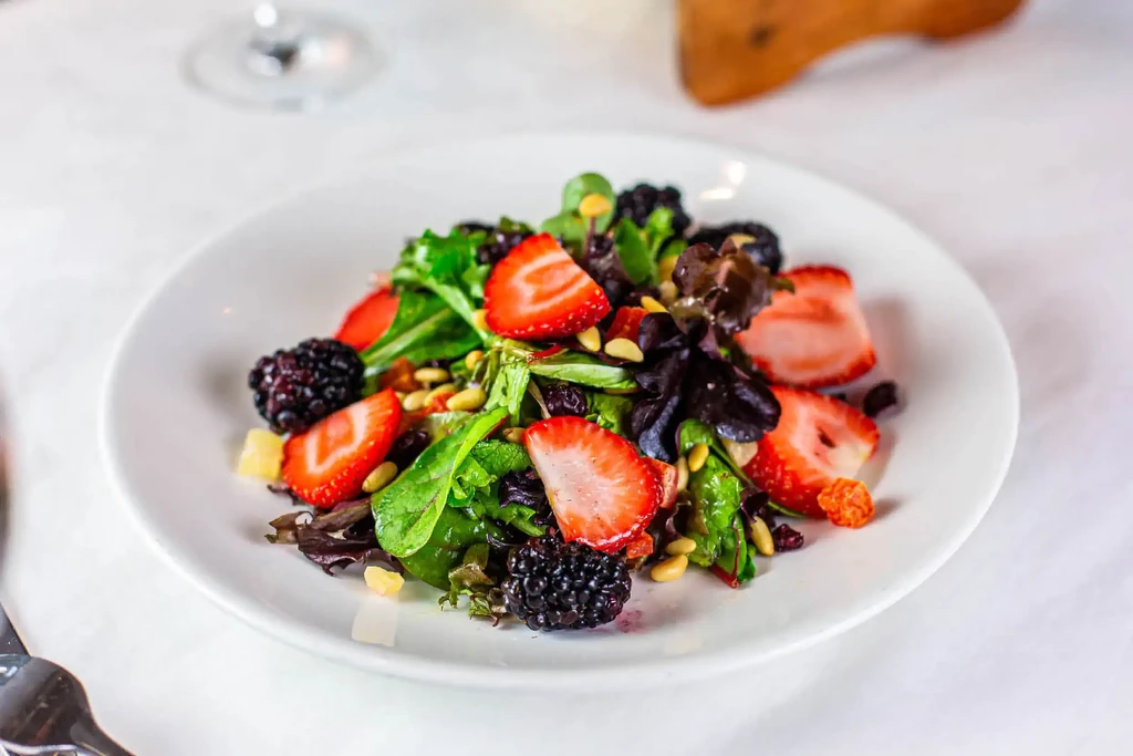 Colorful salad with mixed greens, strawberries, blackberries, and pine nuts.