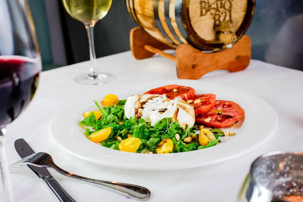 Gourmet burrata salad with arugula, tomatoes, pine nuts, and wine.