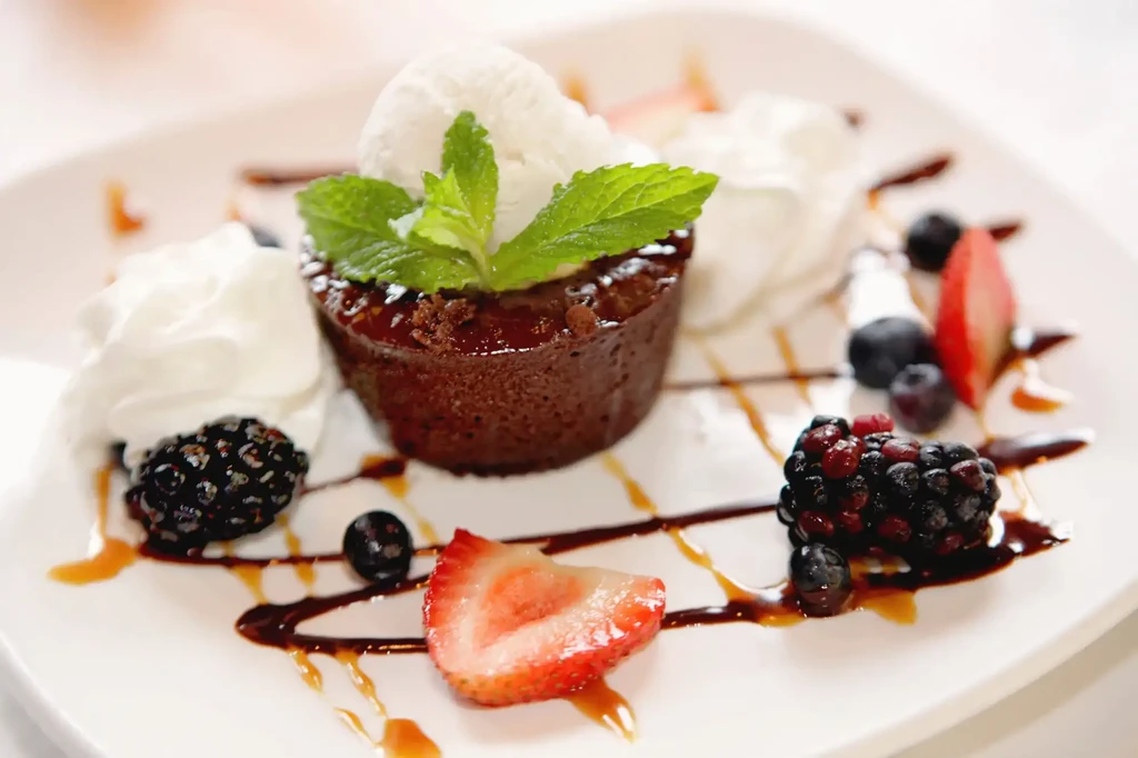 Chocolate cake with vanilla ice cream, berries, whipped cream, and mint.