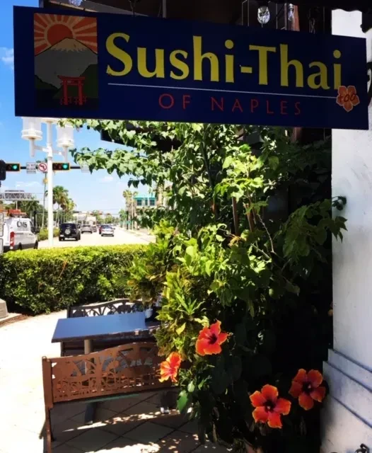 Sushi-Thai of Naples restaurant exterior, blue sign, outdoor dining, hibiscus.