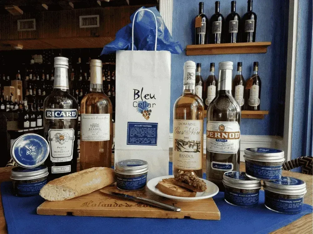 Wine, spirits, tapenade, baguette, and toast in a wine cellar.