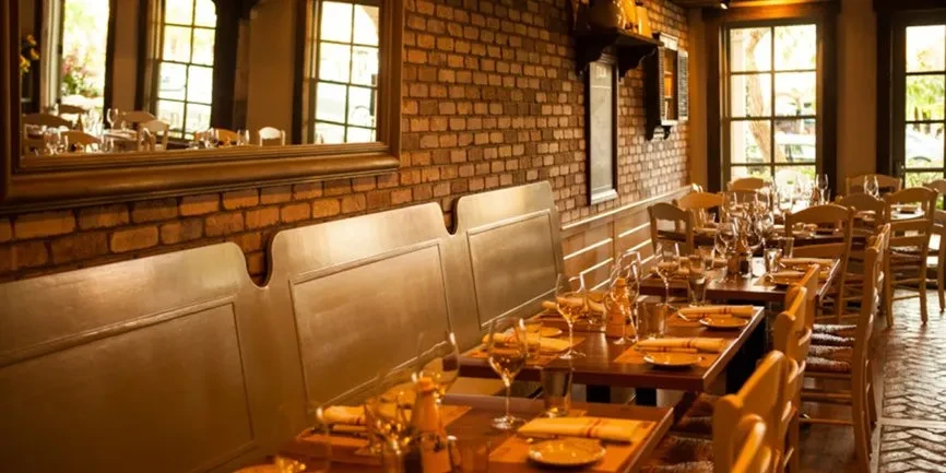 Rustic, empty dining room with set tables and warm natural light.