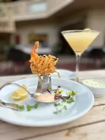 Upright crispy deep-fried shrimp, sauce, lemon, and cocktail.