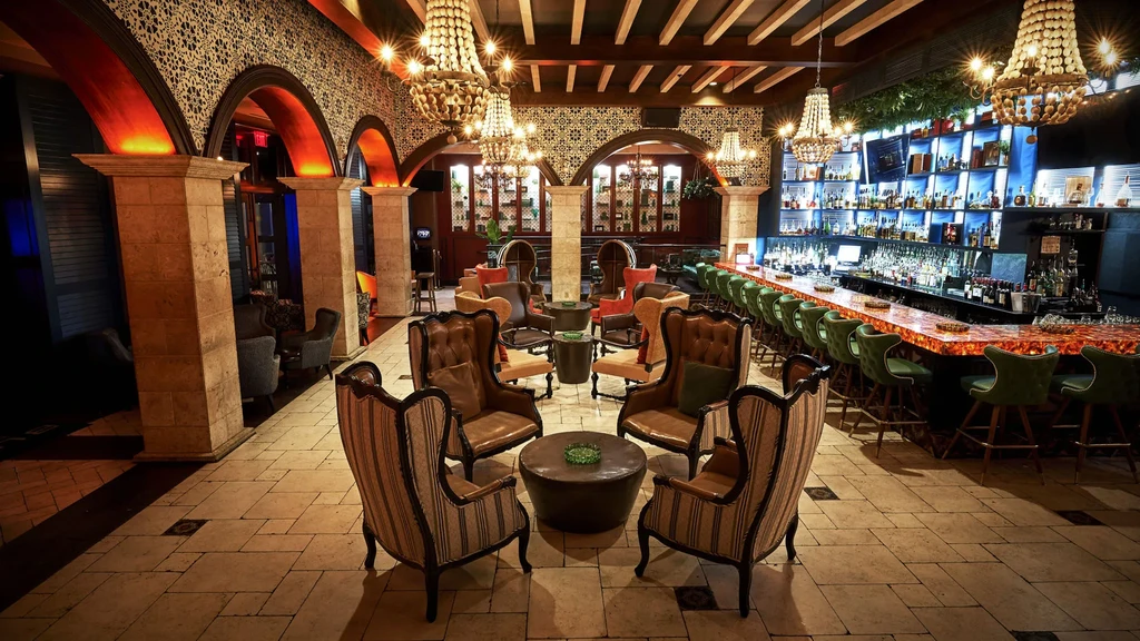 Luxurious restaurant interior with ornate bar, lounge seating, and chandeliers.