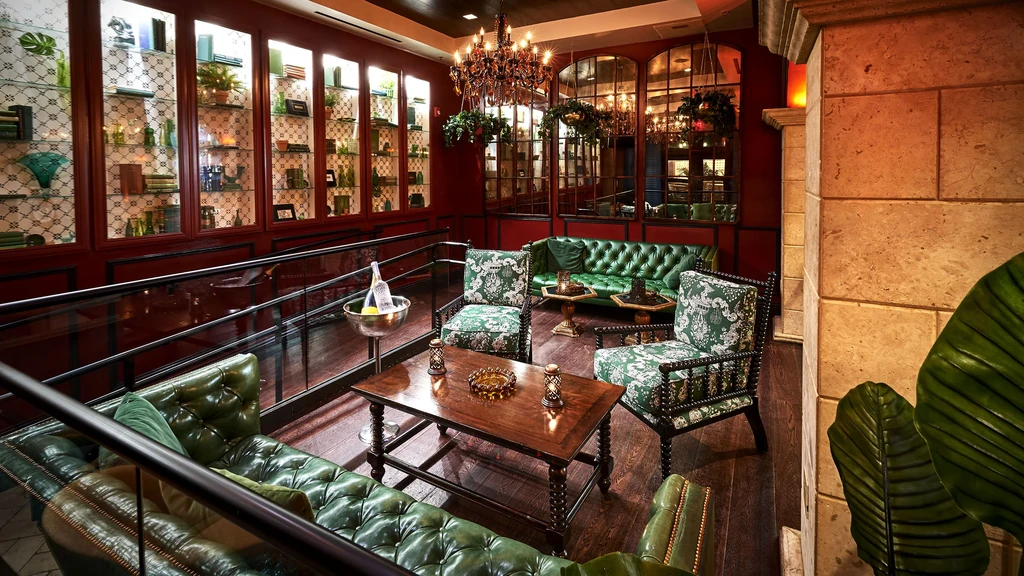 Elegant bar lounge with deep red walls and green tufted sofas.