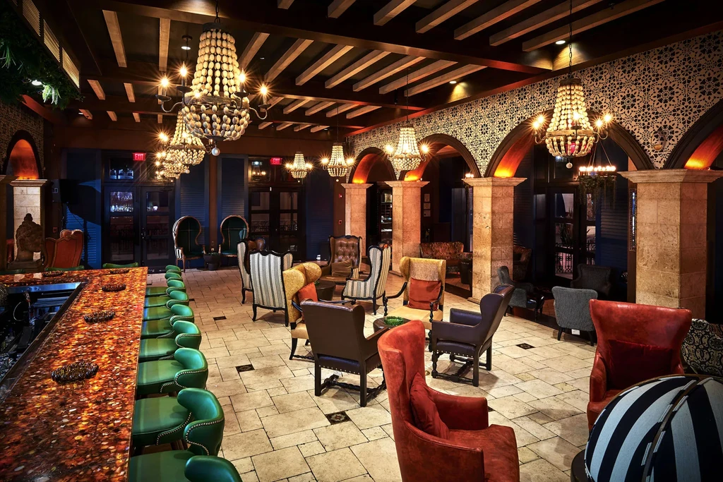 Richly decorated bar lounge with ornate chandeliers and varied seating.